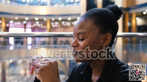 Young african american woman eating fast food in a restaurant enjoying delicious juicy burger