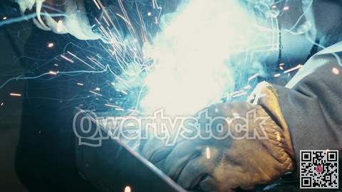 Close-up of a blacksmith welder working with metal using a welding machine, bright sparks and flashes in slow motion