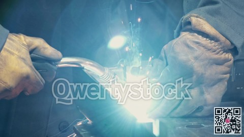 Close-up of a blacksmith welder working with metal using a welding machine, bright sparks and flashes in slow motion