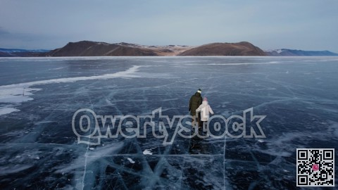 A man-father with a little girl-daughter is skating on the blue transparent ice of the boundless Lake Baikal. Unique places on earth.