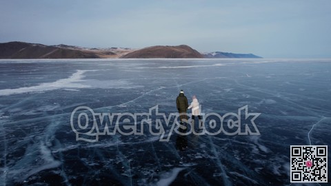 A man-father with a little girl-daughter is skating on the blue transparent ice of the boundless Lake Baikal. Unique places on earth.