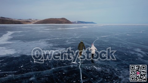 A man-father with a little girl-daughter is skating on the blue transparent ice of the boundless Lake Baikal. Unique places on earth.