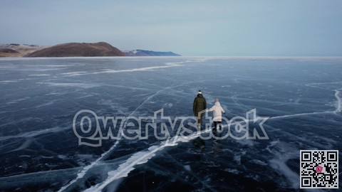 A man-father with a little girl-daughter is skating on the blue transparent ice of the boundless Lake Baikal. Unique places on earth.
