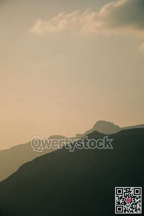 Mountain clouds shadows. Dramatic mountain profile with gentle clouds and shadow play during golden hour