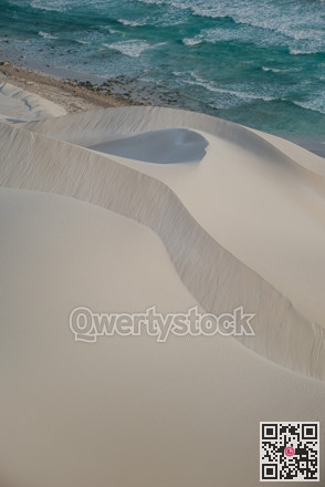Sand meets sea. Vivid coastal scene showcasing sculpted sands and vibrant ocean hues during sunset