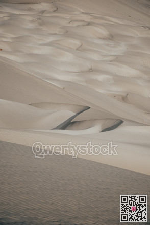 Minimalistic sandy landscape imagery. Soft sunlight accentuates textured dunes with shadows and ripples