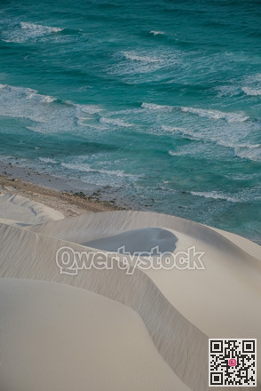 Smooth dunes meet tranquil waters. Graceful sand formations and gentle waves create soothing scenery