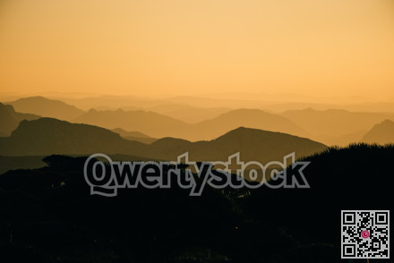 Evoking serene views. Hazy mountain ranges fade into tranquil valleys illuminated by gentle sunlight
