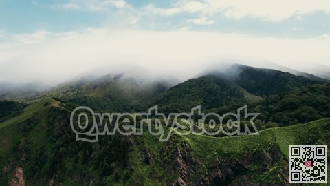 Verdant ridges beneath cloudy skies. Hazy mountains with lush plains and peaceful pathways stretch out