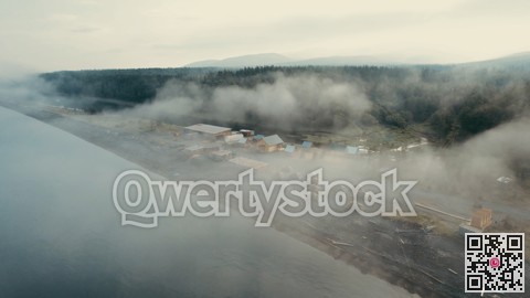Morning fog cloaks peaceful seaside settlement. Gloomy maritime scene with tranquil docks and drifting vessels