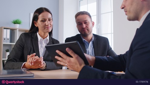 Business people sitting in office during a meeting discussing job project looking at tablet screen. video 1789176
