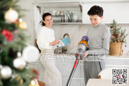 Mother and her teenage son are preparing to celebrate Christmas at home - they are cleaning kitchen, vacuuming floor and washing dishes