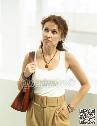 Middle-aged woman walking alone through corridor with wide windows