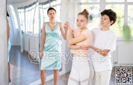 Experienced dance teacher teaching ballroom dancing to a couple of teenagers in studio