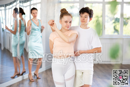 Teenage girl and boy practicing waltz in dance hall with female mentor