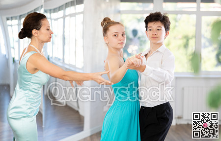 Female dance teacher fine-tuning positions of teenage students during dance class