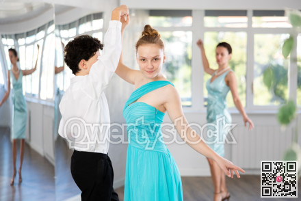 Couple of teenagers in evening dresses are learning to dance an polonaise dance