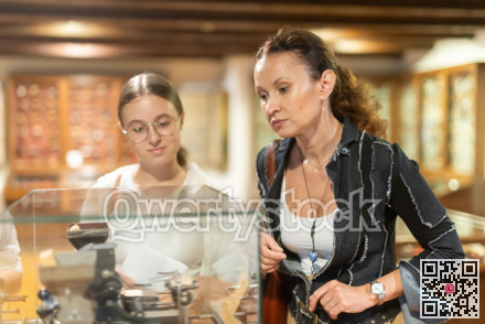 Young woman with teen daughter walk around museum, view clock