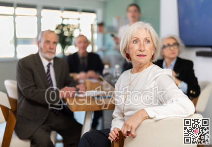 Elderly woman in group watches presentation given by young secretary