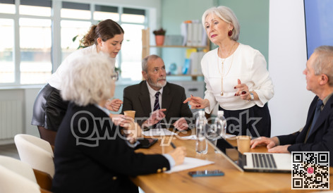 Senior business community listening to female speaker or presenter during round table conference.