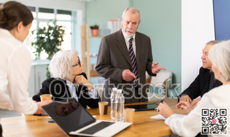 Male boss reprimanding upset subordinates sitting at table in office meeting room, expressing dissatisfaction with work