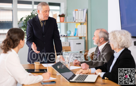 Elderly man leading meeting with senior colleagues at table