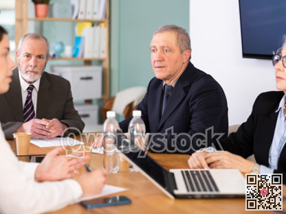 Group of interested business colleagues sitting at table in office, planning work in joint meeting