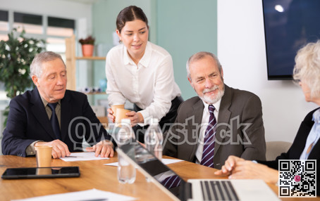 Elderly man leading meeting with senior colleagues at table