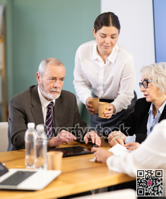 Elderly man leading meeting with senior colleagues at table