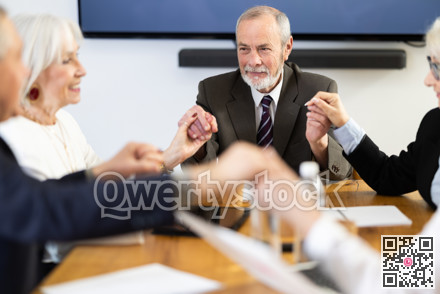 General handshake, with senior business participants holding hands and smiling happily