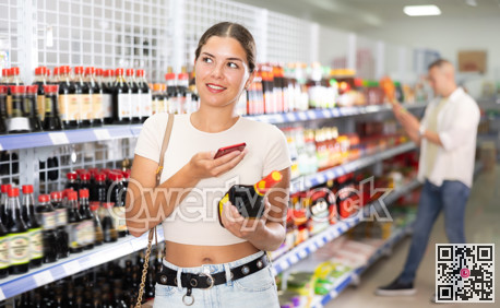 Girl buyer examines packaging of product and scan QR code on bottle soy sauces