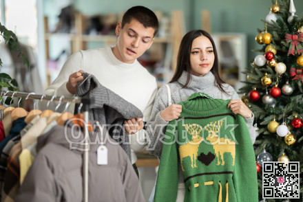 Couple chooses fashionable sweater in a clothing store during Christmas celebrations.