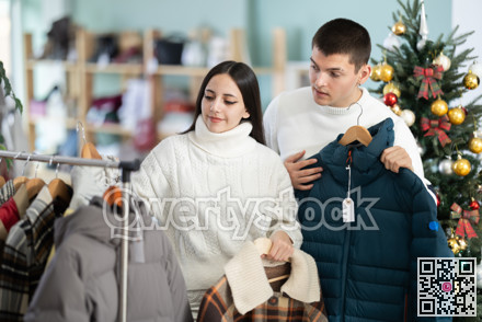 Young couple chooses down jackets in store