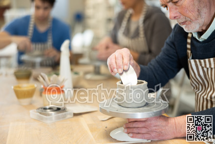 Eldery man sculpts ceramic piece in workshop