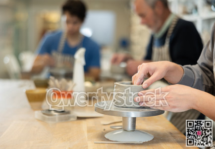 Closeup of female hands sculpting at a table in pottery studio