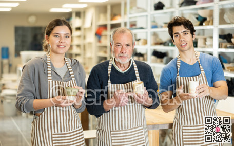 Three positive potters stand in pottery workshop and show created work, finished decorative jug