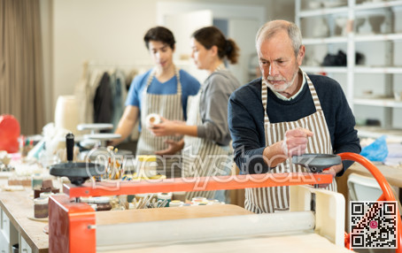 Eldery man rolling raw clay with mechanical slab roller