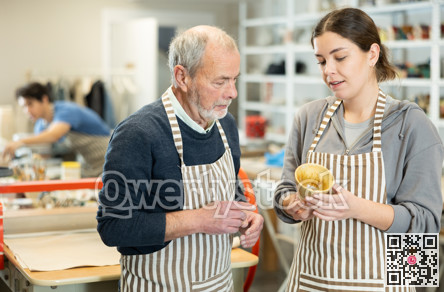 Young woman shows a clay cup she made to craftsman