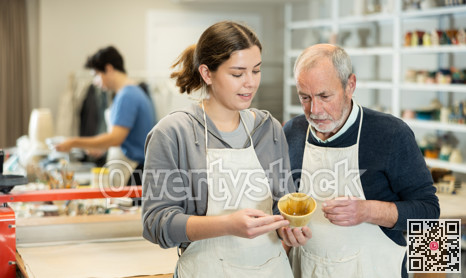 Young woman shows a clay cup she made to craftsman