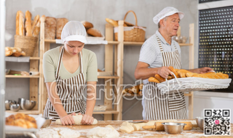 Female baker preparing dough, kneading it on kitchen table