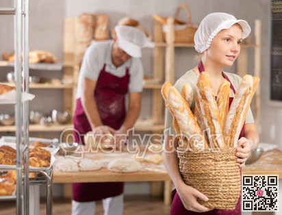Young woman baker with basket of baguettes