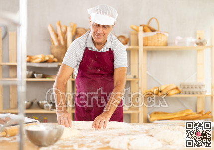 Senior man works as baker in bakery, molds pies from dough, creates croissants from dough.