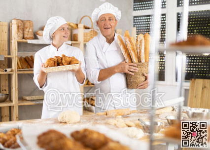 Senior man and girl work as cooks in family French bakery, stand in kitchen with finished products