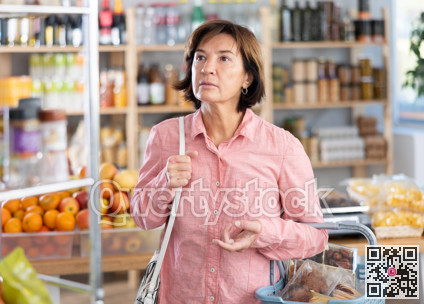 Portrait of female shopper choosing variety of products in grocery hypermarket