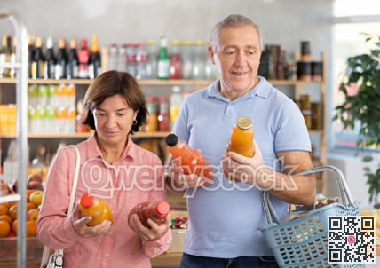 Couple elderly man and woman choosing juices in grocery store