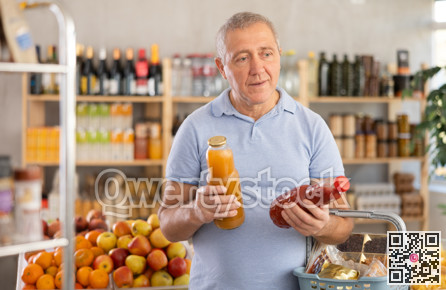 Mature man is choosing natural juice in grocery store