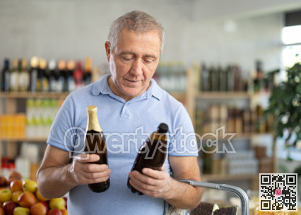 Senior man hold bottle and choose consider beer in store