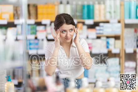 Girl with headache looking for pain relief medicine in pharmacy