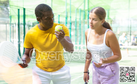 African american man instructor teaches a young woman to play padel tennis