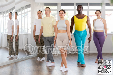 Multinational group of young people stand in row holding hands, performing Irish folk dance.